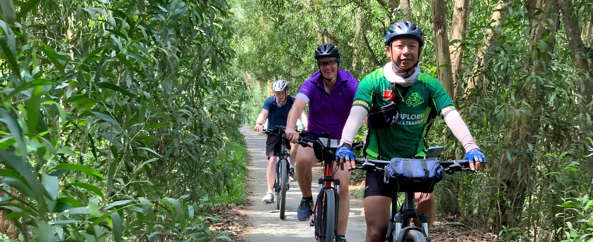 Mr. Kim Linh riding through scenic rice paddies on a bike tour